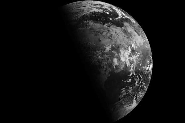 The Earth in black and white on the right side gives way to the planet in shadow on the left.