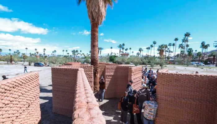 Visitors walk through Ronald Raels Adobe Oasis, which used a huge robotic arm to 3D-print walls of clay and straw in the traditional adobe style. — AFP