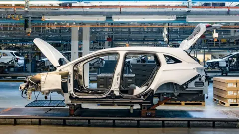Getty Images A white car half-built on the production line, with its boot and bonnet open