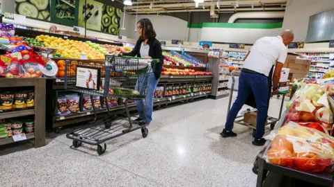 EPA-EFE/REX/Shutterstock A woman pushes a grocery cart while shopping for groceries at a supermarket.